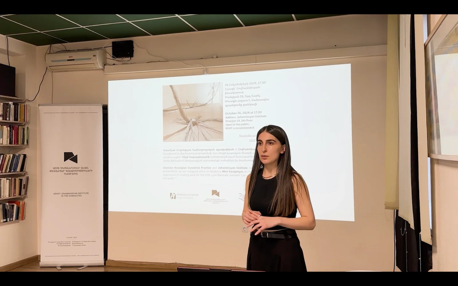 Mery Karapetyan presenting her work beside a projected image.