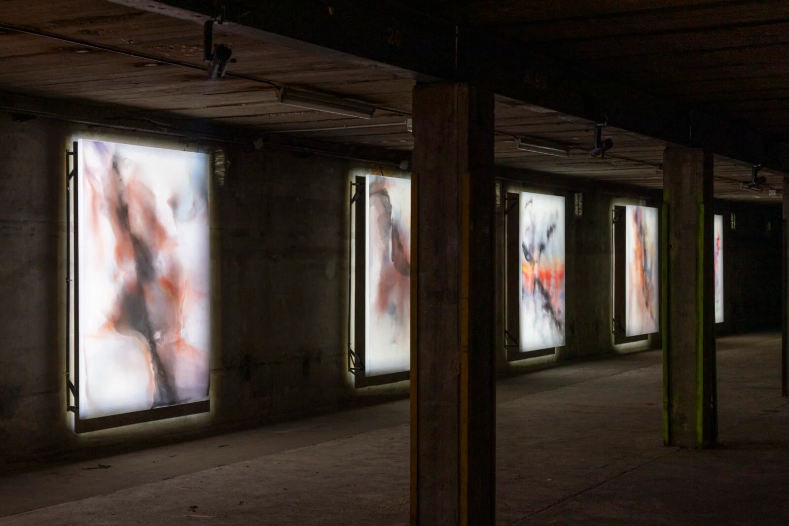 Illuminated artworks inside a dark exhibition hall at the Lyon Biennale.