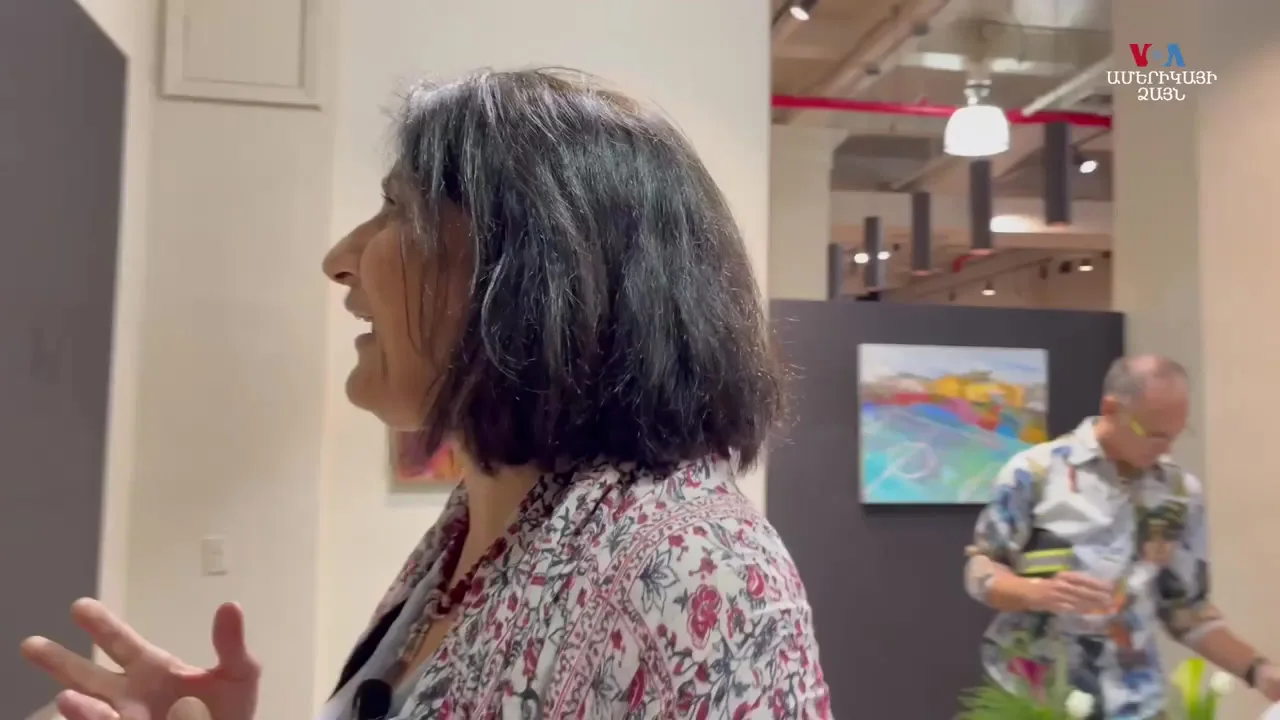 An artist speaking in front of artworks.